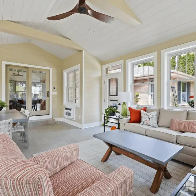 Four-season sunroom with white plank ceiling, ceiling fan and windows on three sides