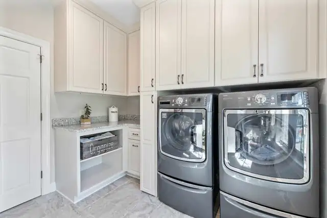 Laundry room remodel with white cabinets to the ceiling, front-load washer and dryer and open shelf