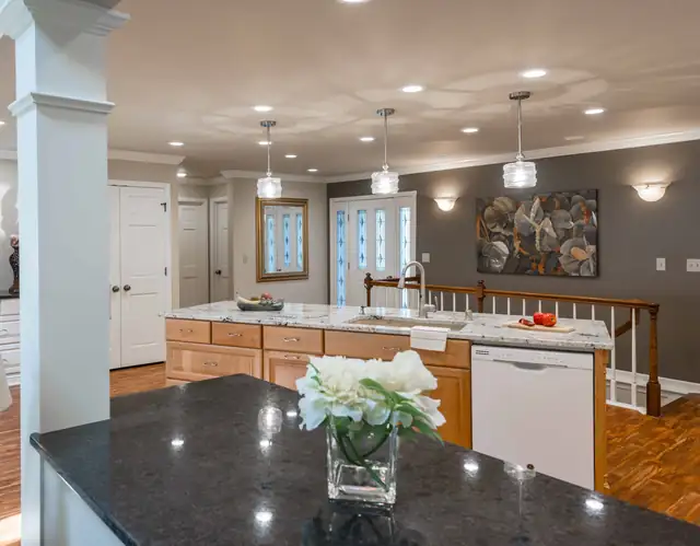 Hartland, WI kitchen remodel with dark granite island top, wood cabinets, glass pendant lights and an open sightline to the dining area