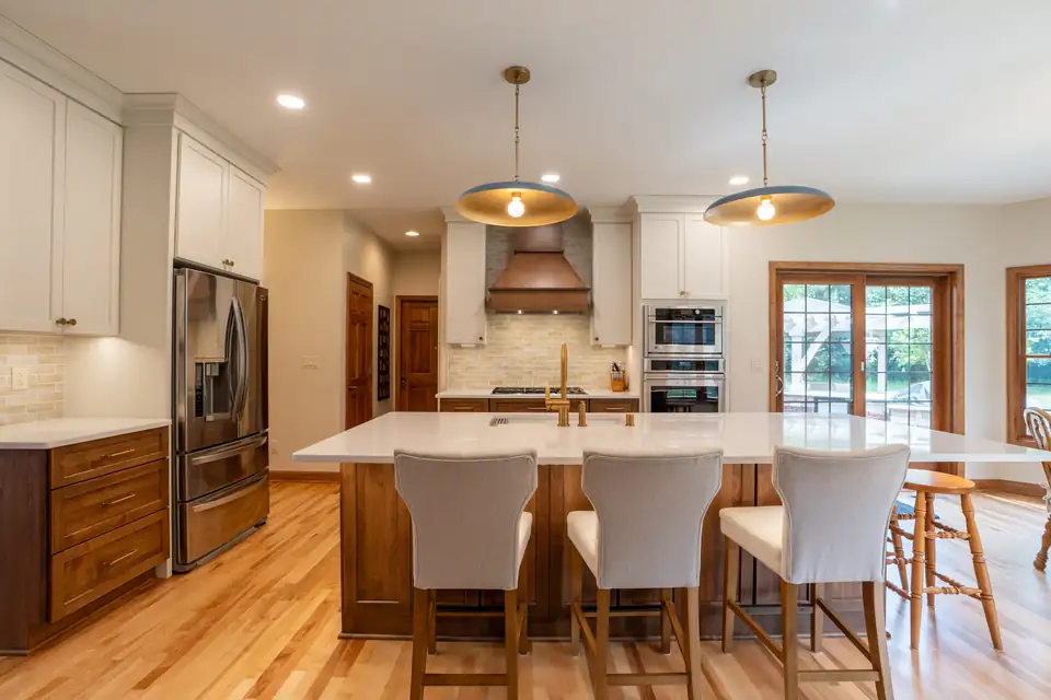 Kitchen remodeling Waukesha County project in Sussex, WI by GMH Construction: walnut island with white quartz top, copper range hood, brass pendants and white cabinets